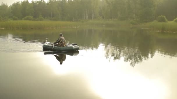Ψαράς ο άνθρωπος επιπλέει σε μια λίμνη σε ένα φουσκωτό σκάφος. Νωρίς το πρωί — Αρχείο Βίντεο