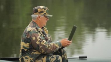 Bir dizüstü bilgisayar, göl üzerinde çalışan bir adam. Bir balıkçı bir olta ile