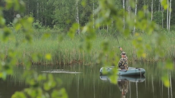 Рыбак на лодке рыбачил. Маленькая рыбка на удочке — стоковое видео