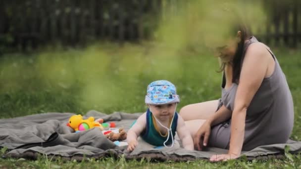 Chłopiec dziecko siedzi na łące, stara się jeść trawa — Wideo stockowe