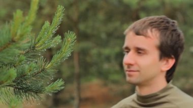 Adam ağaç ve ondan damlayan çiğ dokunuyor. Gülen adam