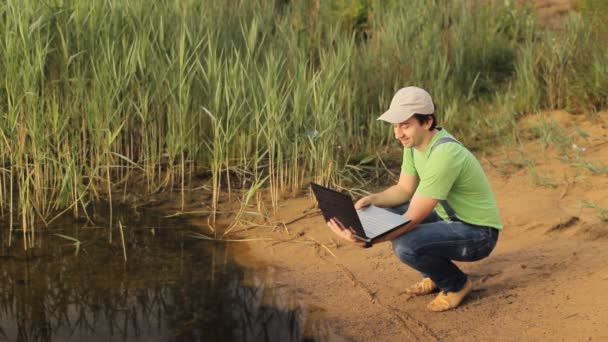 Человек, разговаривающий на видео на ноутбуке на побережье — стоковое видео