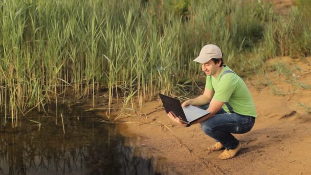 Un homme parle sur une vidéo sur un ordinateur portable sur la côte — Video