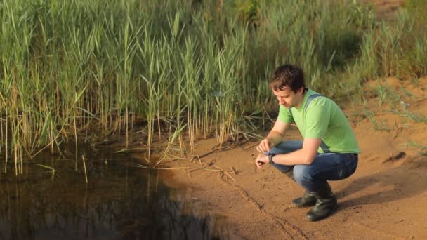 Man touch smartwatch på sjön. Vacker strand med sand och gräs — Stockvideo