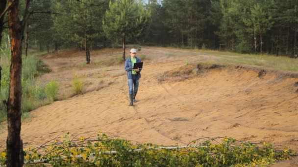 Un homme en bottes marchant sur une plage de sable avec ordinateur portable — Video