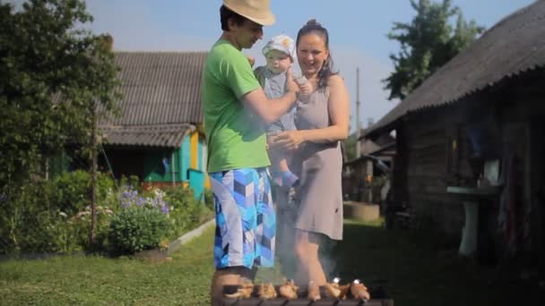 Vater und Mutter der Kinder kochen Fleisch auf dem Feuer. Grill ist fast fertig — Stockvideo