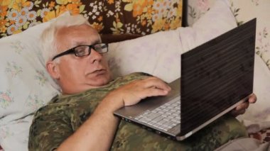Evde dizüstü bilgisayar ile yatakta komuta sizde. Onun mide üstünde laptop
