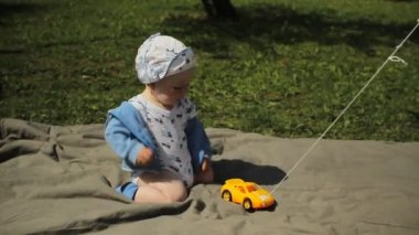 Şirin oynak sarışın 1 yıl yaşlı çocuk yeşil üzerinde oturan çim açık oyuncakları ile oynarken gülümsedi