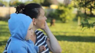 Erkek bebek anne parkta tarafından tutun. Anne telefonu arama.