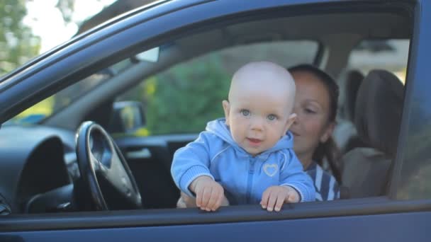 Мать с ребенком сидит в машине на водительском сидении. Детская игра с улыбкой — стоковое видео