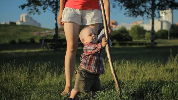 Mère se tient dans le parc près des arbres et tient son petit garçon souriant. Enfant toucher arbre — Video