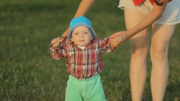 Mutter spielt mit ihrem kleinen Sohn im Park. das Kind macht die ersten Schritte — Stockvideo