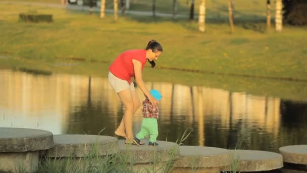 Boldog anya és fia utazik a természeti park, folyó napsütéses napon. Nő, kis fiú baba, gyermek, gyerek, nyaralás. Gyönyörű természeti táj. A család kiadási időt együtt a szabadban — Stock videók