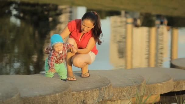 Щаслива мати і син подорожують в природному парку, на річці в сонячний день. Жінка, маленький хлопчик, дитина, дитина у відпустці. Прекрасний ландшафт природи. Сім'я проводить час разом на відкритому повітрі — стокове відео