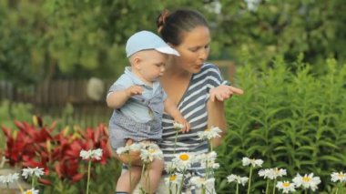 Genç anne ile çiçek evinin yakınında dokunmadan onun güzel çocuk. Oğlu bitkiler dikkatle görünüyor