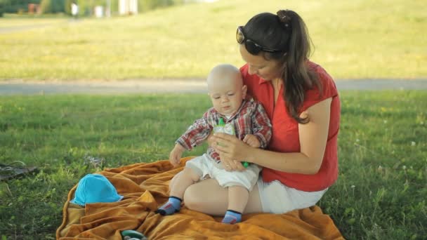 Famiglia felice di tre persone sdraiata sull'erba nel parco estivo. Giocano e sorridono — Video Stock