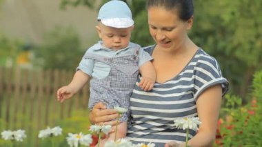 Genç anne ile çiçek evinin yakınında dokunmadan onun güzel çocuk. Oğlu bitkiler dikkatle görünüyor