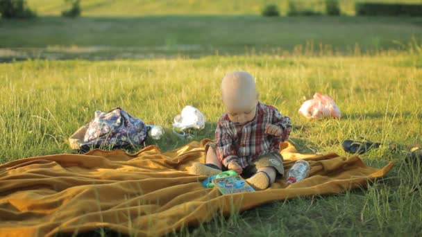 Joli petit garçon assis sur une couverture dans le parc. Bébé moins d'un an et il a joué — Video