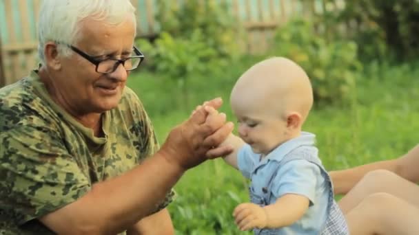 Boldog család játszik egy kis kisgyermek fiú egy nyári parkban, gyönyörű fű. Anya, Baby, nagyapja — Stock videók