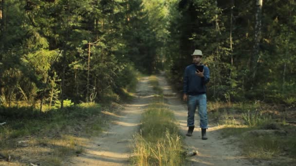 Un hombre camina por el bosque con una tableta PC y mirando la aplicación de navegación. Él elige la dirección correcta — Vídeos de Stock