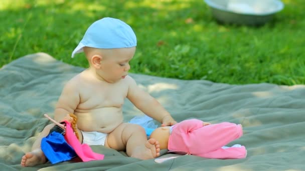 Encantador bebé jugando en el jardín con una pequeña muñeca y cochecito — Vídeo de stock