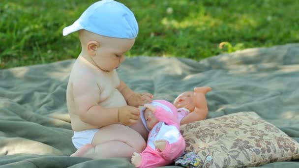 Encantador bebé jugando en el jardín con una pequeña muñeca y cochecito — Vídeos de Stock