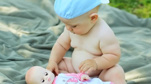 Encantador menino brincando no jardim com uma pequena boneca e carrinho — Vídeo de Stock