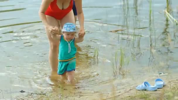Mãe e avô brincando com o menino no lago. Menina bonita anda na água — Vídeo de Stock