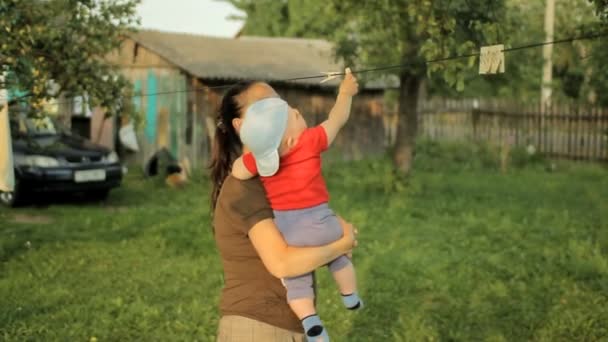 Mamá juega con el bebé en un hermoso jardín con pinzas de ropa. Adorable bebé menos de un año — Vídeos de Stock