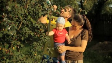 Mutlu bir aile bebeği ile bahçede oynarken. Anne, baba, oğul, gülümseme ve gülmek
