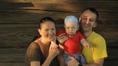 Eski bir ahşap ev gülümseyerek mutlu bir aile. Anne, baba, evlat, kameraya gülüyor