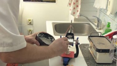 Diş teknisyeni, diş laboratuarında eklem makinesi ile çalışıyor.