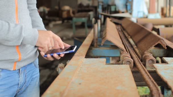 La mano maschile tiene un moderno telefono touch screen e sfoca l'immagine della vecchia fabbrica — Video Stock