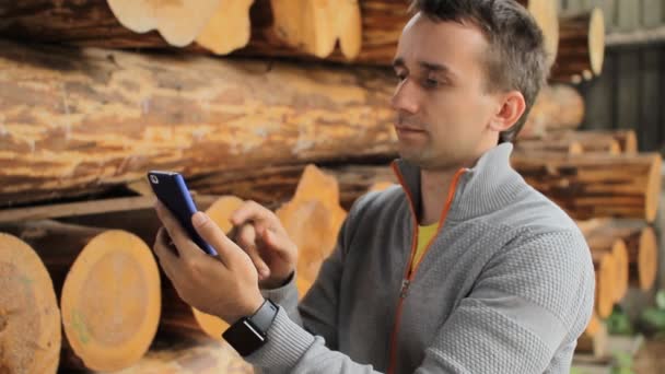 Young man forestry engineer touch phone in front of wood — Stock Video