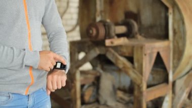 Erkek el bir modern dokunmatik ekran telefon tutarak ve eski fabrika görüntüsünü bulanıklık