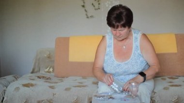 Yaşlı hasta kadın evde istenen tablet seçer. O zaman alır ve onun suyu içer