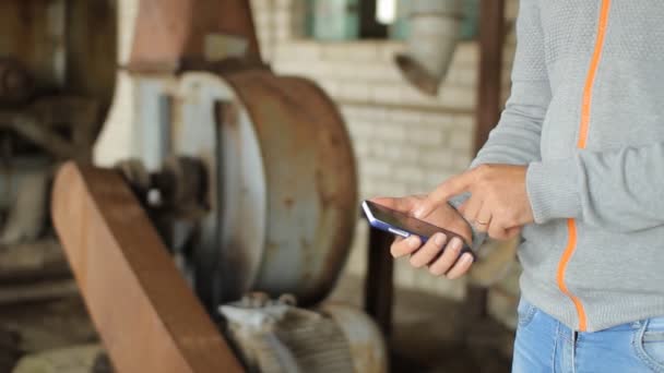 Erkek el bir modern dokunmatik ekran telefon tutarak ve eski fabrika görüntüsünü bulanıklık — Stok video