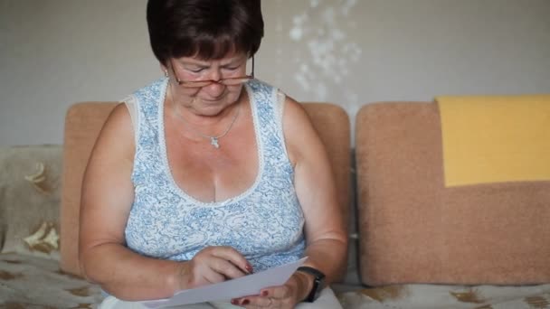 Mujer mayor firmando un contrato en casa. Ella lee cuidadosamente y firma el documento — Vídeos de Stock