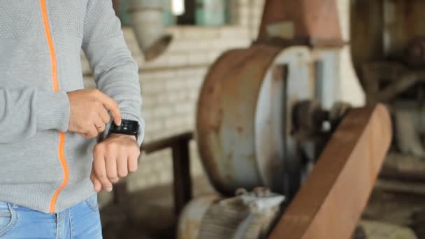 La mano maschile tiene un moderno telefono touch screen e sfoca l'immagine della vecchia fabbrica — Video Stock