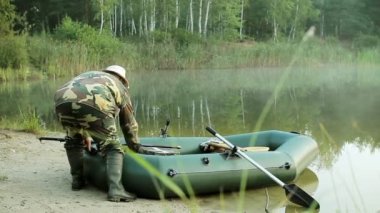 Kürek ile şişme bir tekne kıyısında bir balıkçı yelken. Erken sabah sis su ile. vahşi doğada tatil.