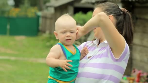 Dítě jen sestříhané vlasy a narovná maminka účes. Na dvoře kolem domu — Stock video