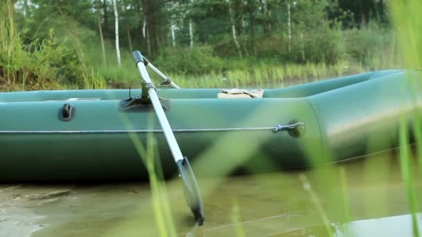 Зелений надувний човен, що стоїть на пляжі зі своїми веслами. переміщення камери — стокове відео