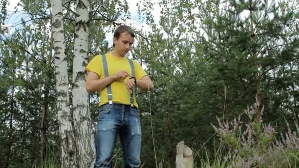 Человек-турист ходит по лесу и трогает умные часы. Желтая футболка и джинсы с подтяжками. Технологии в дикой природе — стоковое видео