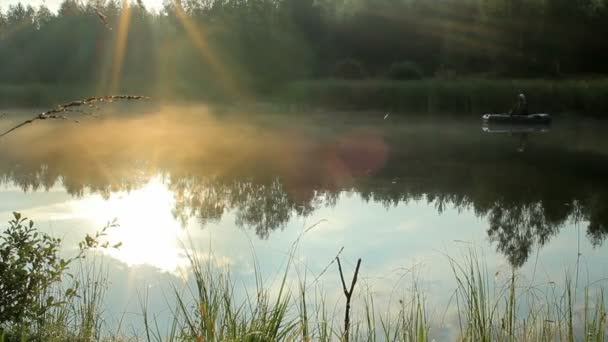 Le pêcheur flotte sur la rivière dans un bateau gonflable. Les rayons du soleil jouent dans le cadre. Activités dans la nature — Video