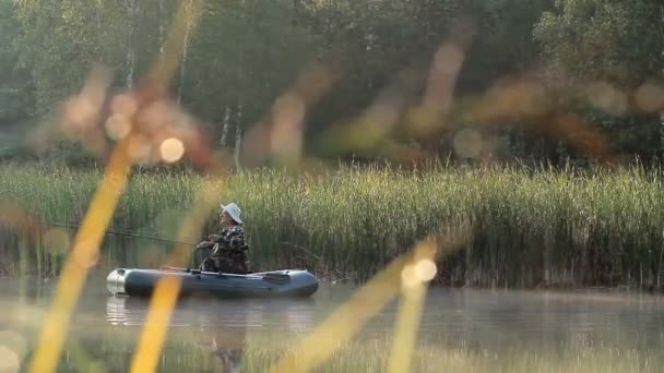 Le pêcheur flotte sur la rivière dans un bateau gonflable. Les rayons du soleil jouent dans le cadre. Activités dans la nature — Video