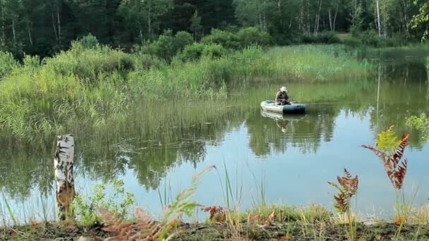 Il pescatore galleggia sul fiume su una barca gonfiabile. Telecamera in movimento tramite cursore. Attività in natura — Video Stock