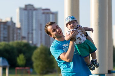 Parkta babası ile First Steps erkek bebek. Yazın bir sürü yeşil çimen ve ağaç etrafında.