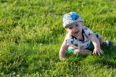 Sevimli bebek çocuk oynarken ve parkta gülüyor. Yaz kırıntıları için yeşillik ilginç şeyler bir sürü civarındadır. Çocuk 1 yıl