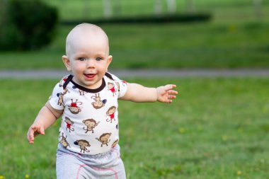 Sevimli bebek çocuk oynarken ve parkta gülüyor. Yaz kırıntıları için yeşillik ilginç şeyler bir sürü civarındadır. Çocuk 1 yıl