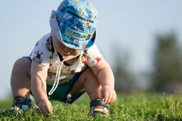 Lindo niño jugando y riendo en el parque. El verano es alrededor de un montón de vegetación cosas interesantes para migajas. Niño 1 año — Foto de Stock